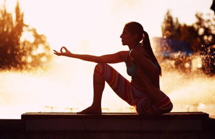 Young native american woman doing yoga on the street in summer