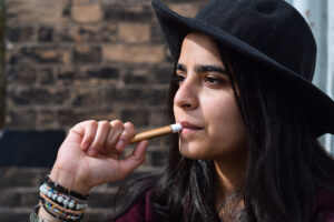 young girl in black hat holding vaping e cigarette