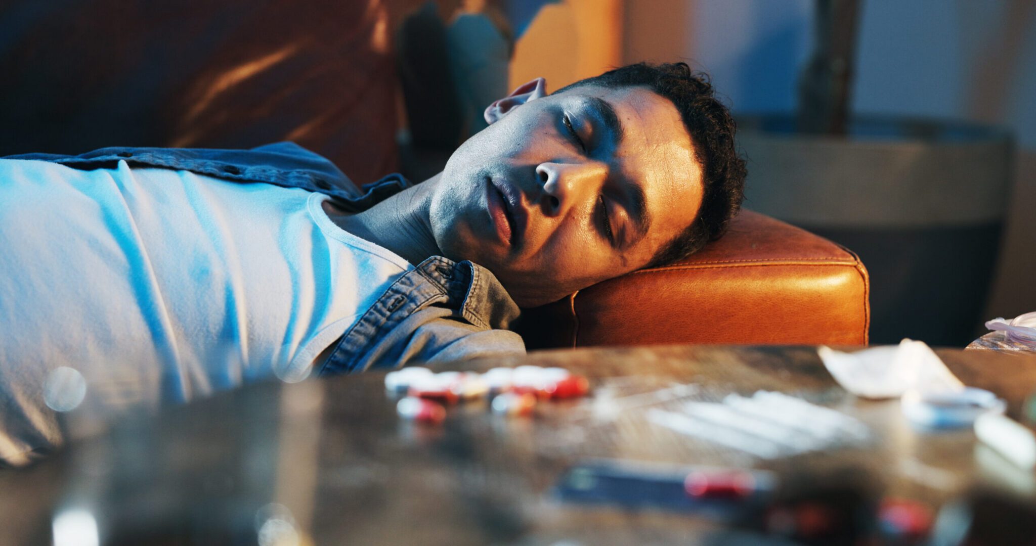 Drugs, overdose and man on couch with pills
